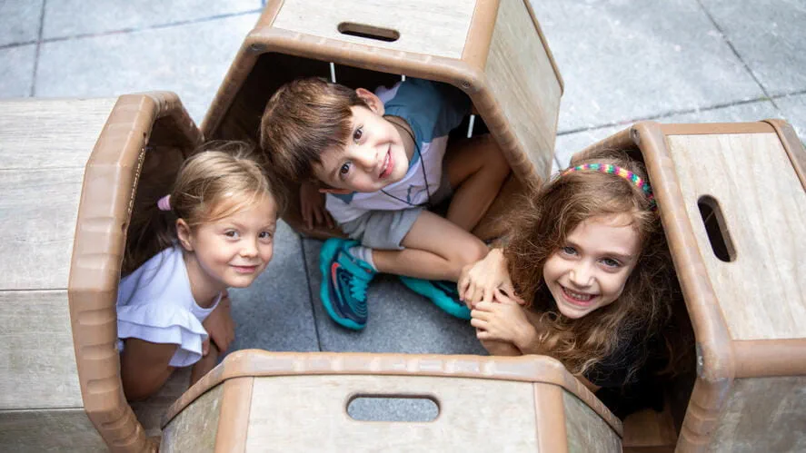 Children playing inside a cardboard box den